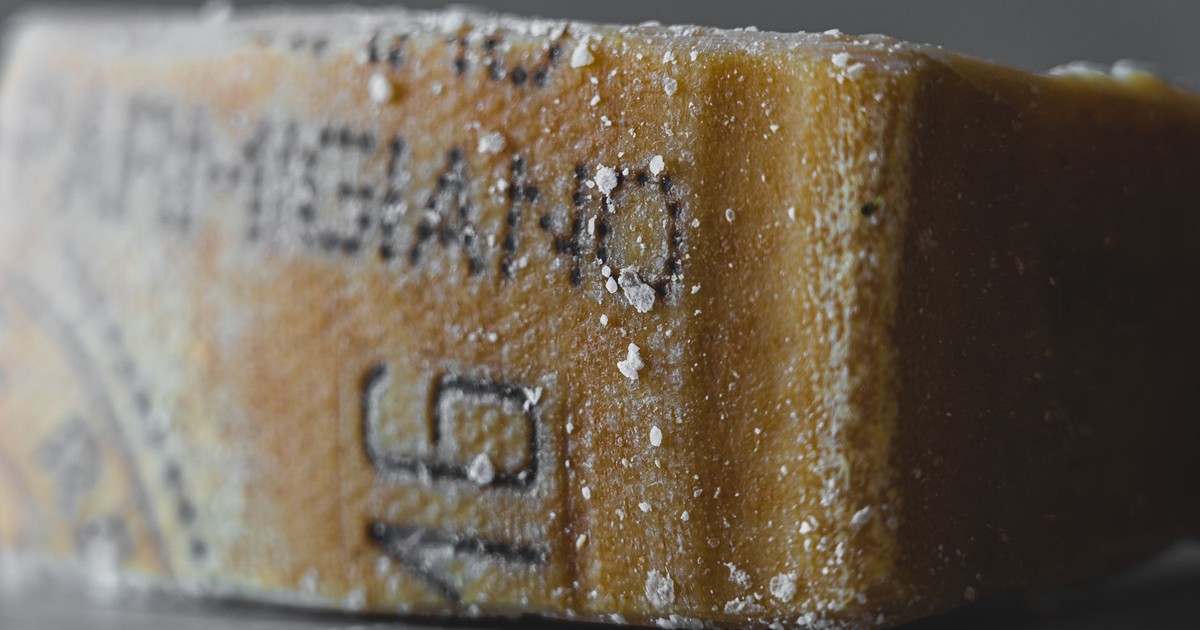 Detailed close-up of an aged Parmigiano cheese block, showcasing texture and salt crystals.