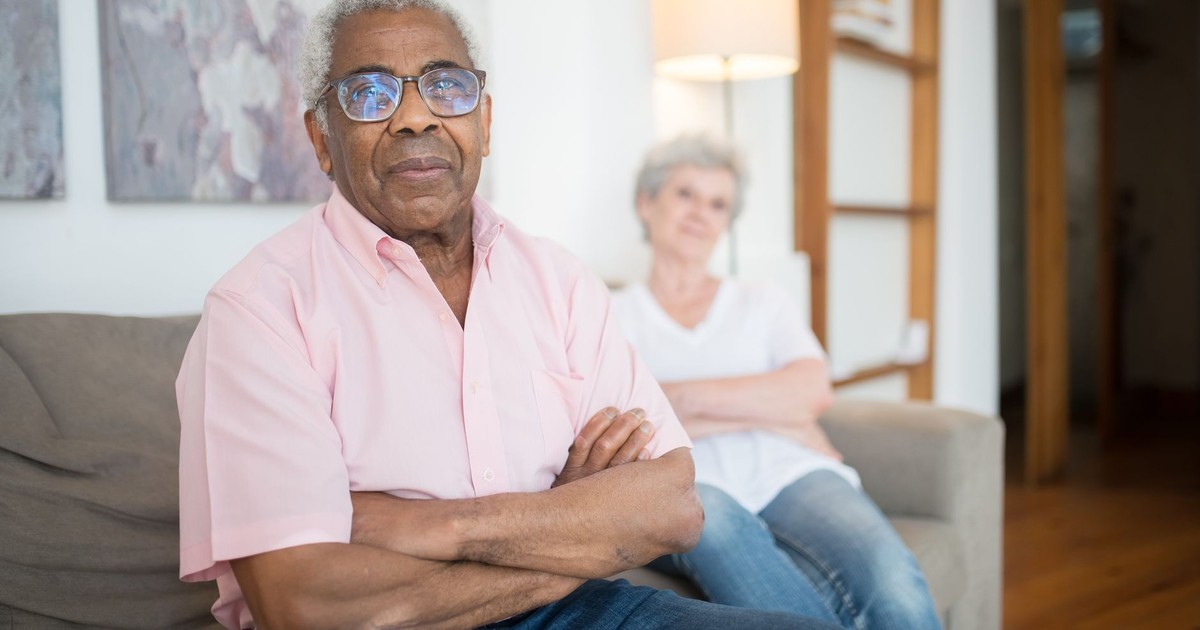 Two senior adults sitting comfortably on a sofa in a cozy living room setting.