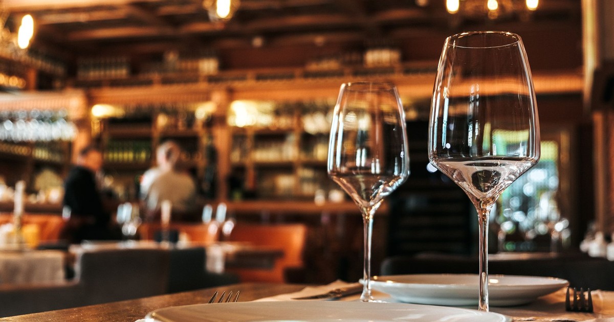 Elegantly set dining table with glassware in a cozy, warmly-lit restaurant ambiance.
