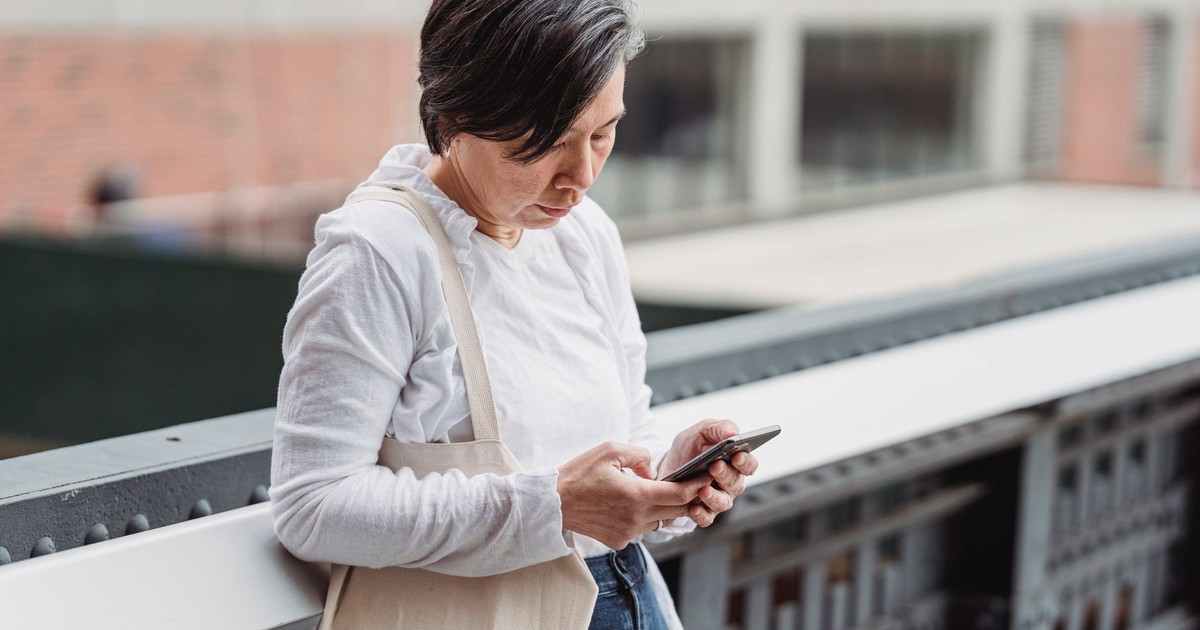 Casual scene of a woman interacting with her smartphone outdoors, leaning on railings.