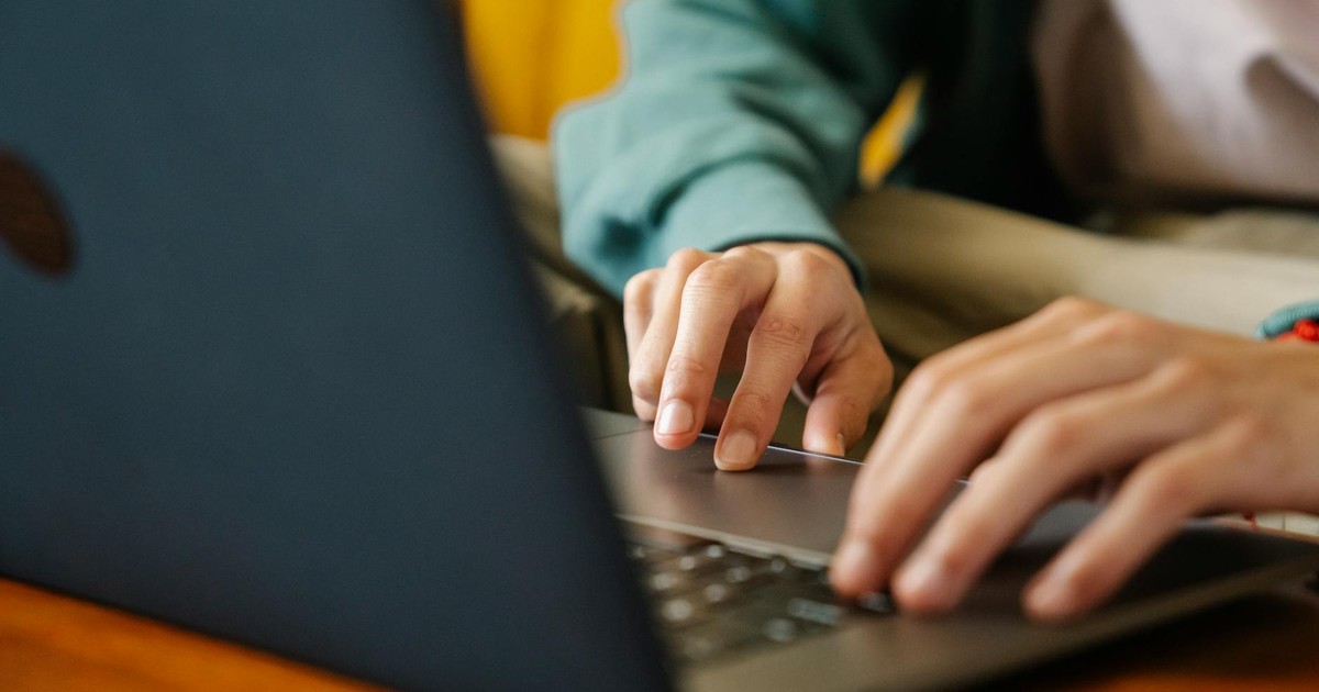 Crop unrecognizable distance employee surfing internet on netbook while working on project at desk in room