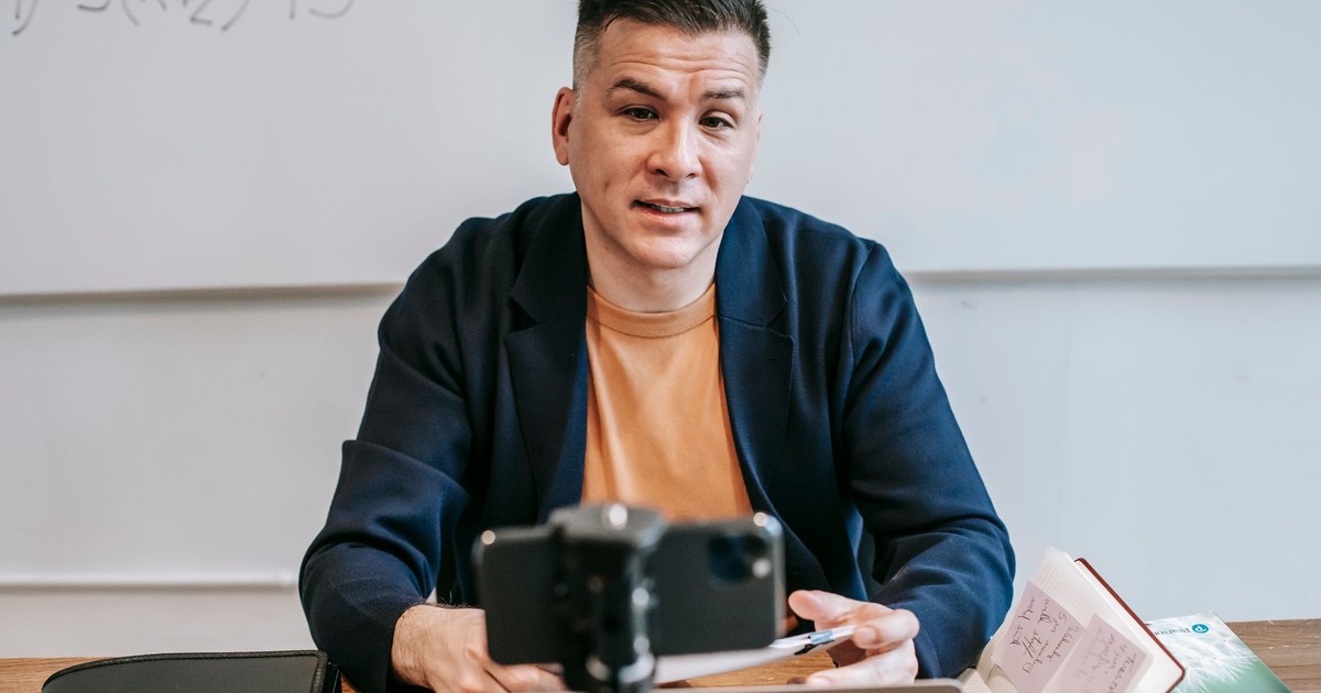 A professional educator conducting an online class, engaging with students via video call.