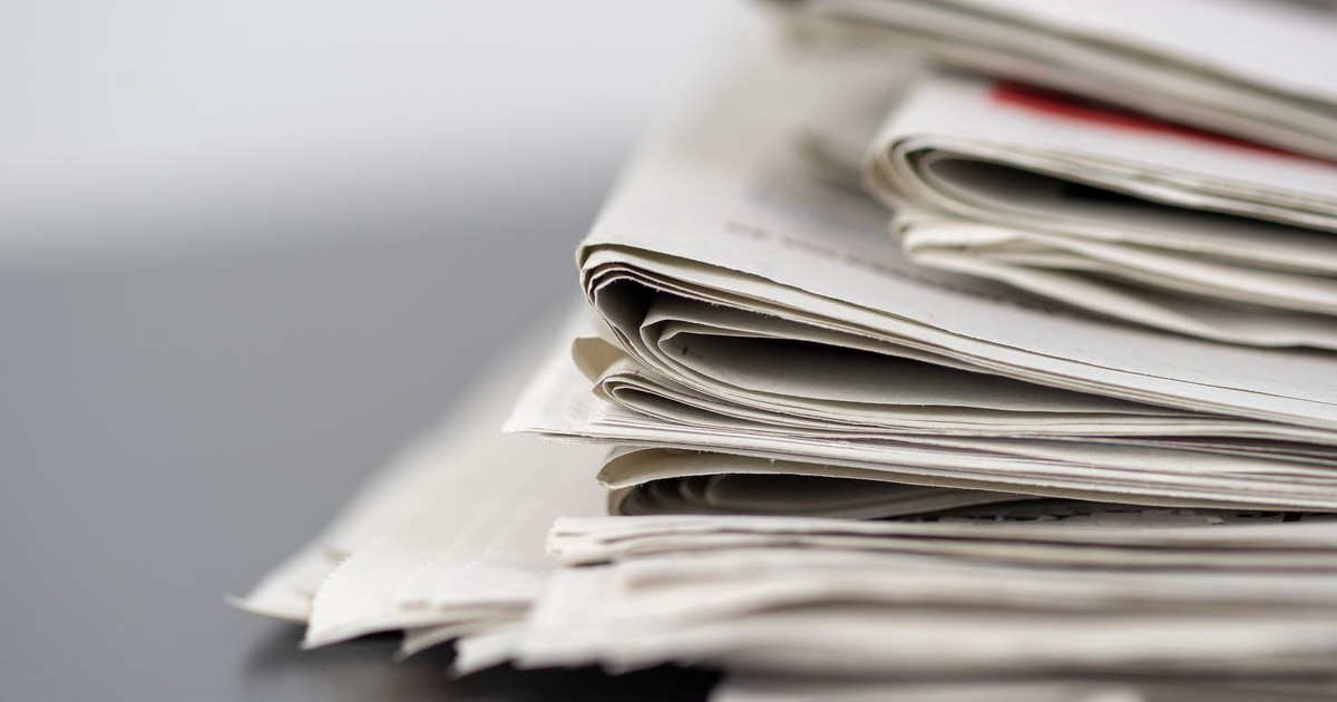 Close-up of stacked newspapers on a table, representing media and journalism.