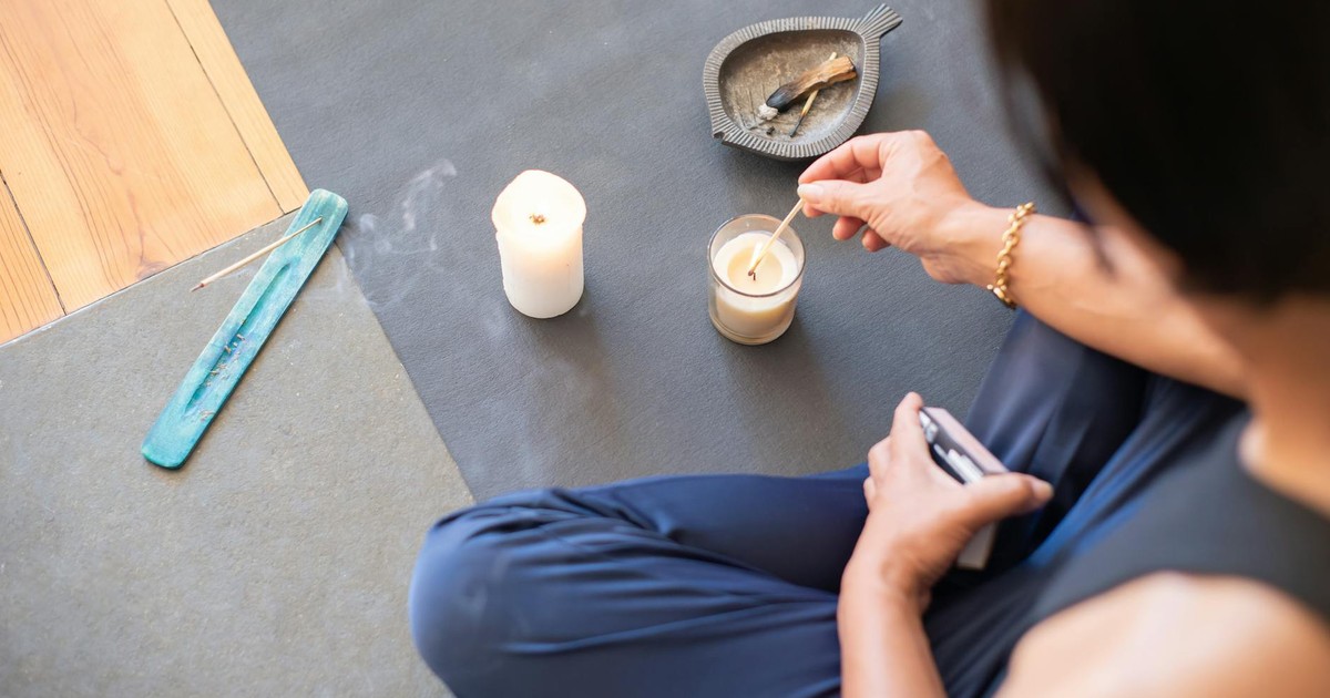 A person engages in a calming ritual with candles and palo santo, creating a serene atmosphere.
