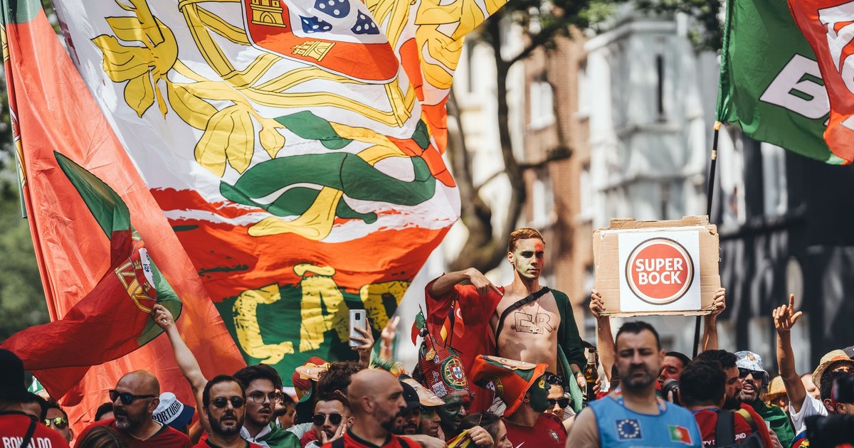 Energetic crowd of Portuguese fans with flags cheering during street parade.