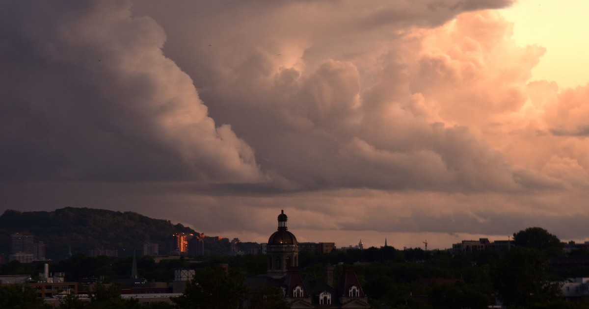 A dramatic view of storm clouds over a city skyline during dusk, highlighting an iconic dome structure.