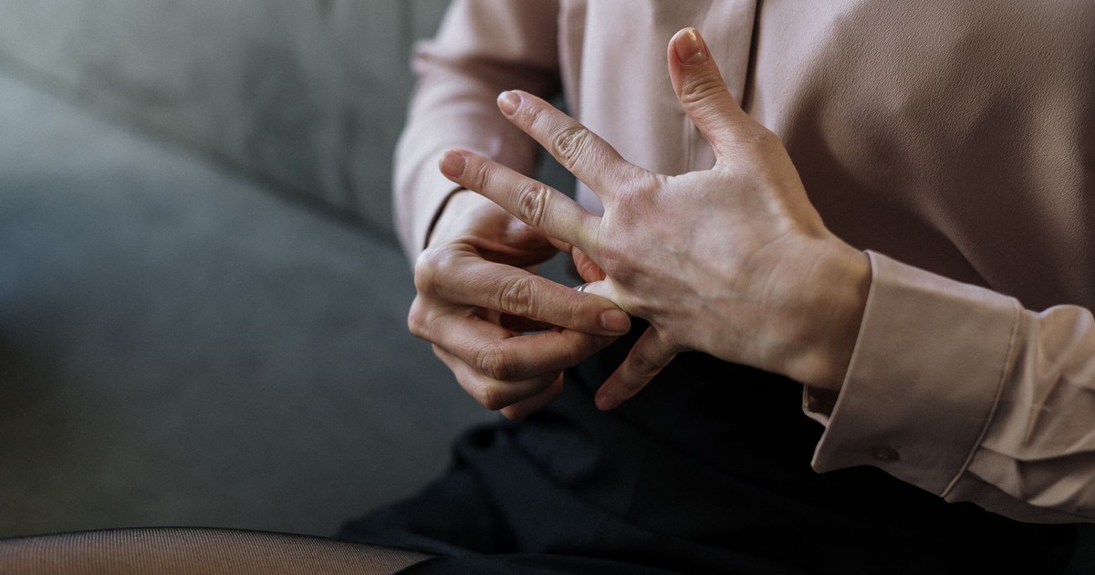 Close-up of a person removing a wedding ring, symbolizing relationship change or decision.