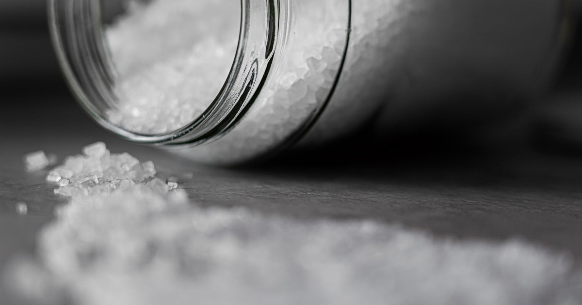 Detailed image of rock salt pouring out from a glass jar with a selective focus effect.