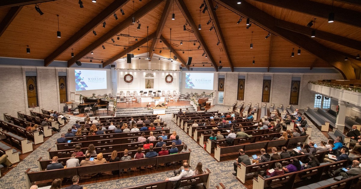 Large congregation gathered in church with wooden interiors, engaged in a service.
