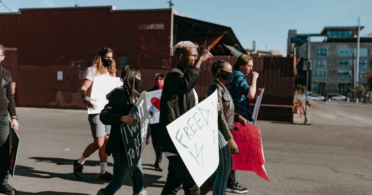 A diverse group of individuals peacefully rallying for freedom in an outdoor urban setting.