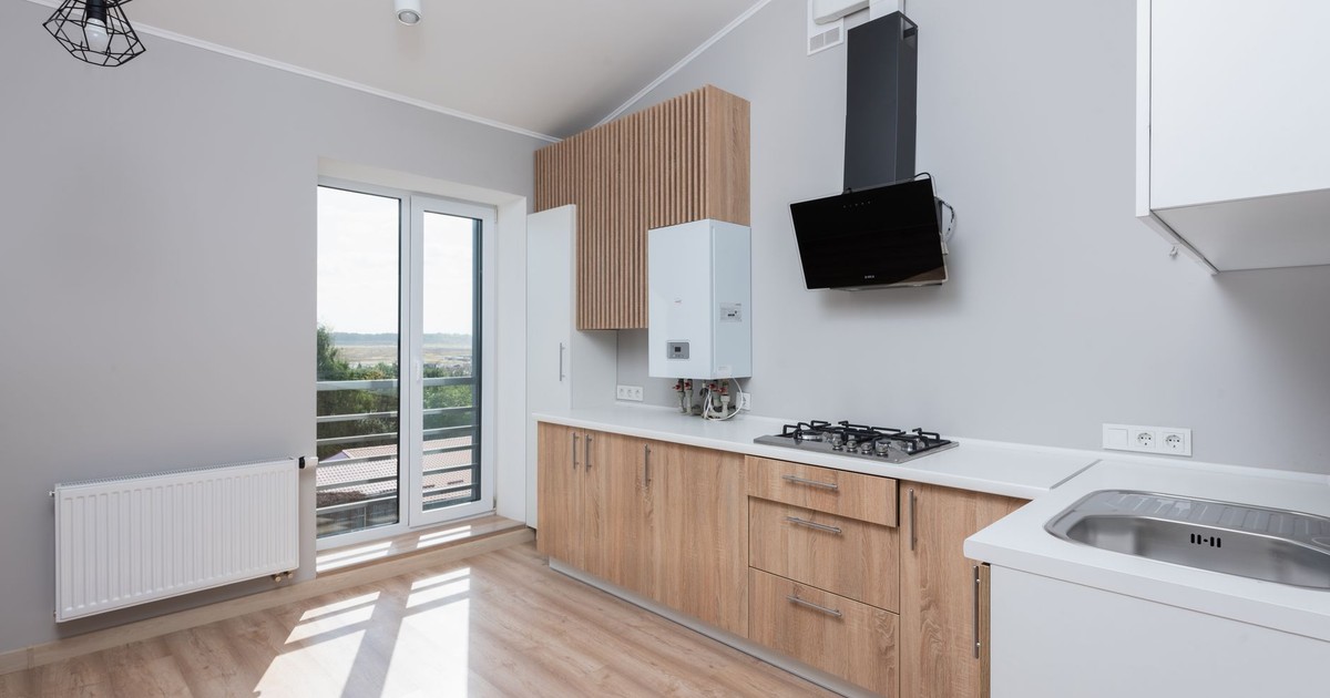 Stylish empty kitchen with wooden cabinets and large windows.