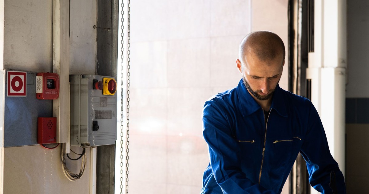 Caucasian male technician working indoors with PPE in industrial setting.
