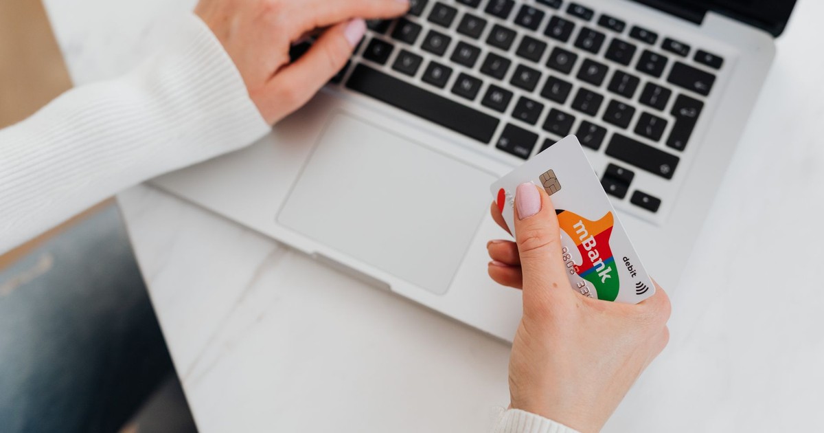 Close-up of a person using a laptop and holding a credit card for online shopping.