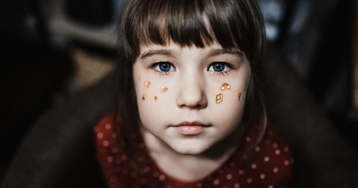 A young girl with face stickers poses in a thoughtful portrait indoors.