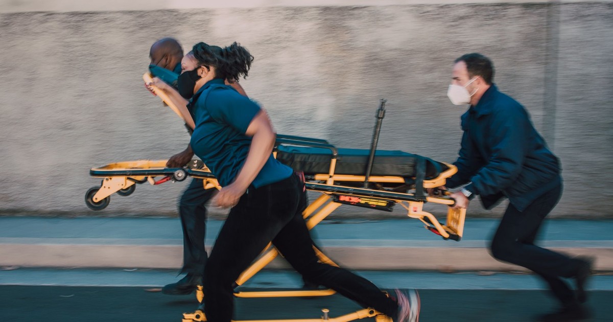 Dynamic shot of paramedics running with a stretcher on a street, showcasing urgency and teamwork.