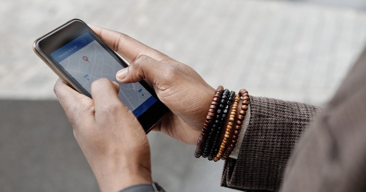 Close-up of hands with bracelets navigating on smartphone using GPS app outdoors.