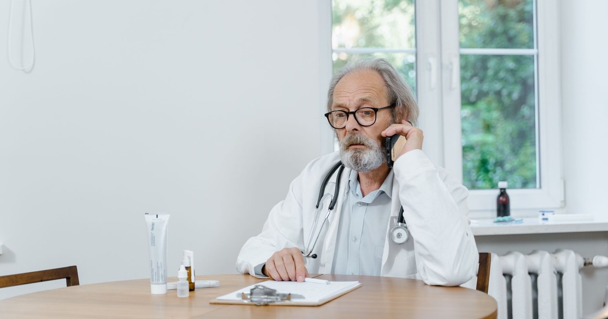 A senior doctor making a telemedicine call in an office setting, discussing medical cases.