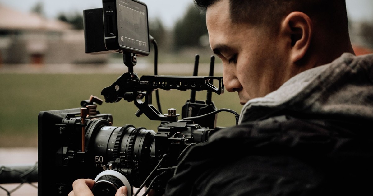 A cameraman using professional equipment for filming outdoors, focused on capturing high-quality footage.