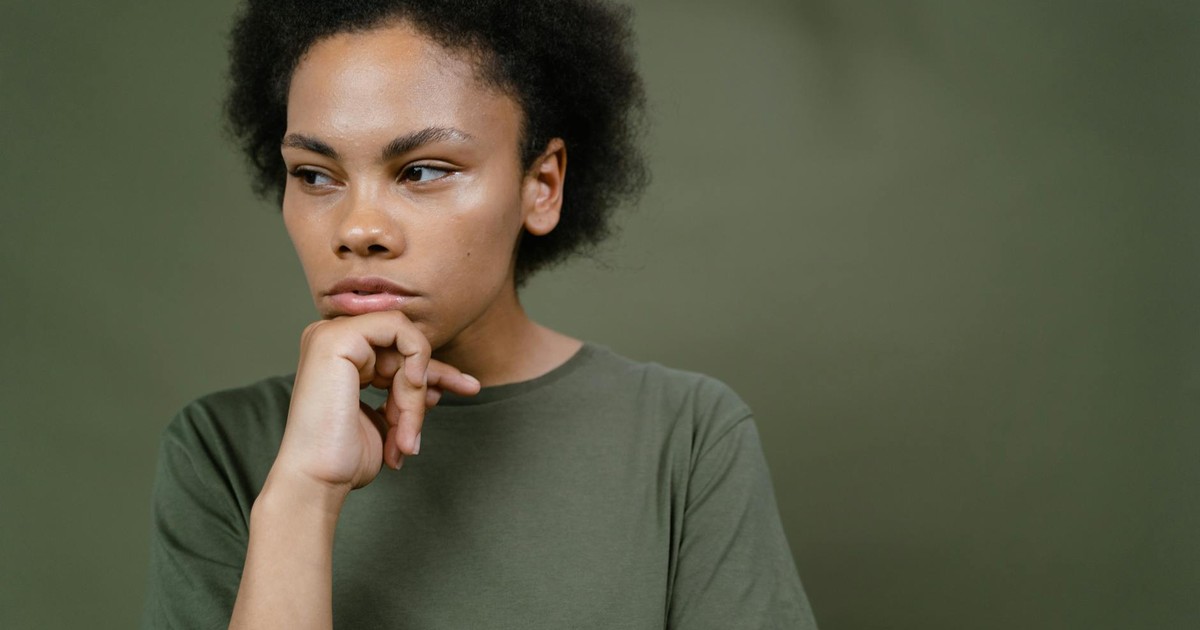 A pensive young woman with afro hair contemplating and looking away, emphasizing individuality and emotion.