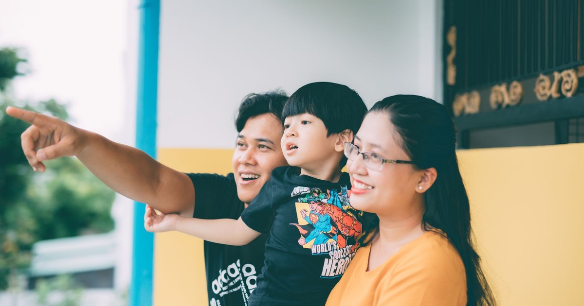 Asian family enjoying togetherness outdoors, pointing at something with smiles.