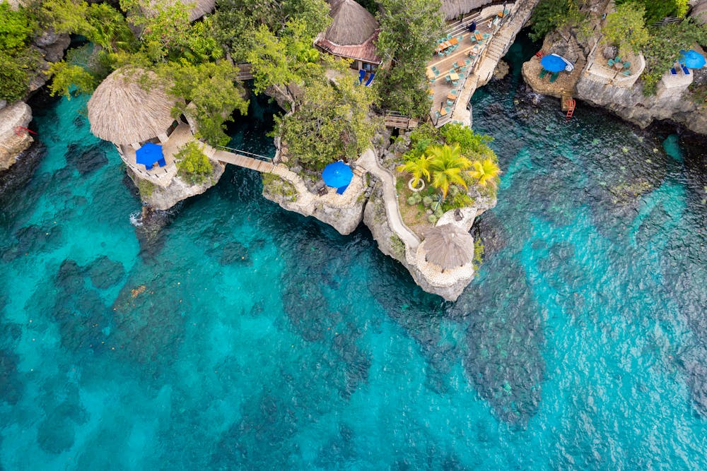 Stunning aerial view of a cliffside resort in Negril, Jamaica, featuring turquoise waters and natural architecture