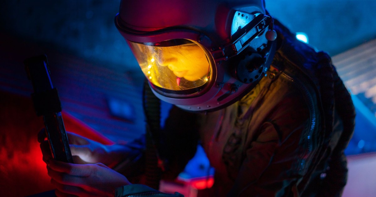 A female astronaut explores a futuristic environment with bright blue and red lighting.