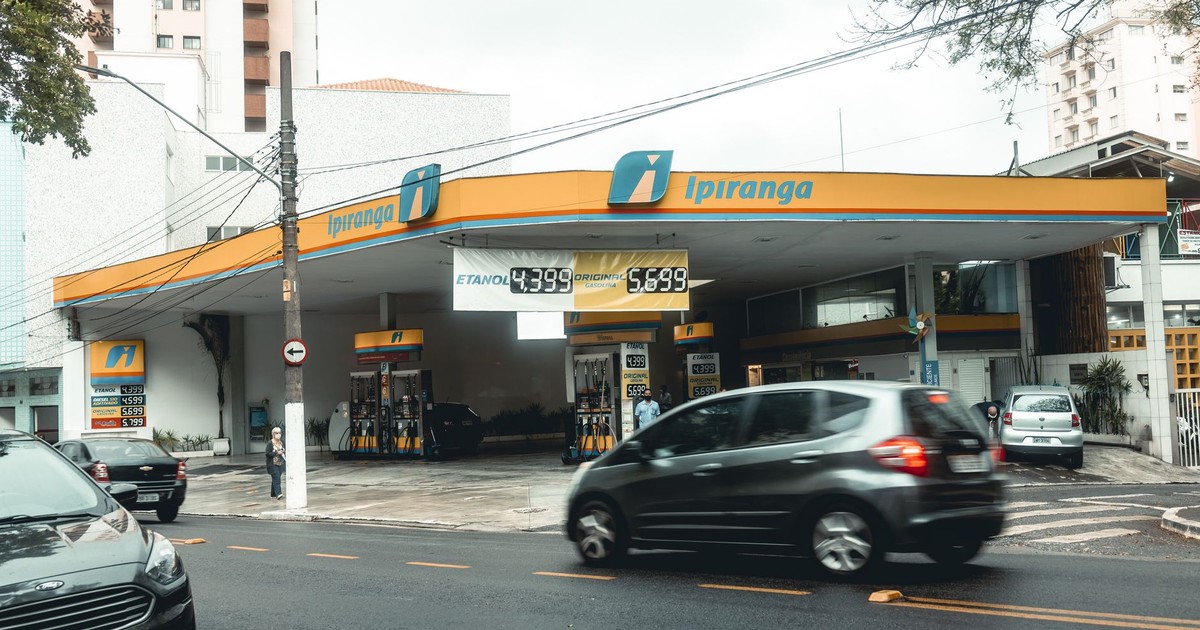 Ipiranga gas station with moving vehicles on a bustling city street.