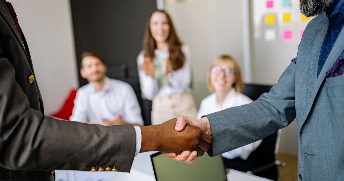 Close-up of a handshake between colleagues in a professional office setting, emphasizing teamwork and agreement.