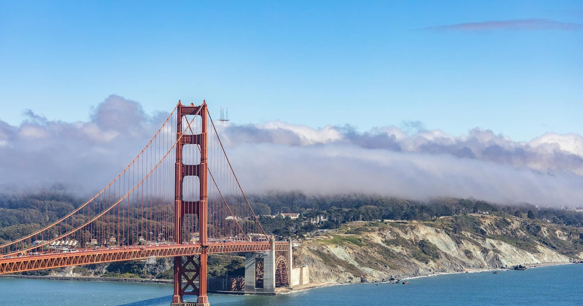 A stunning aerial view of the iconic Golden Gate Bridge with clouds and a blue sky in San Francisco.