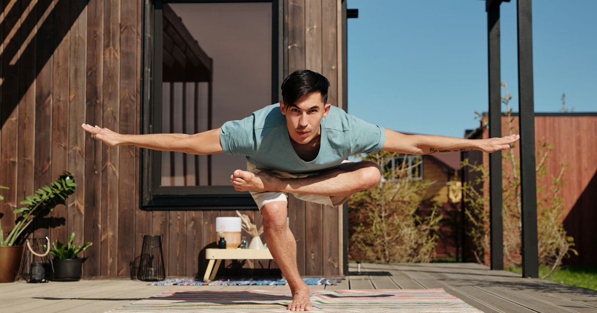 A man performing a yoga pose on a veranda outside, embracing a balanced and healthy lifestyle.