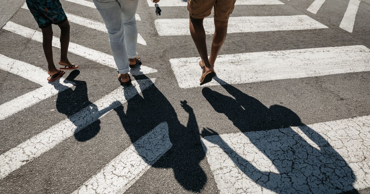 A family walking across a zebra crossing, representing safety and care.