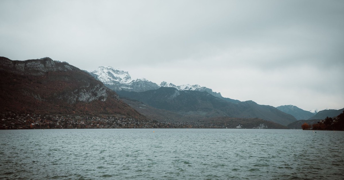 Tranquil view of Lake Annecy with snow-capped Alps mountains in autumn.