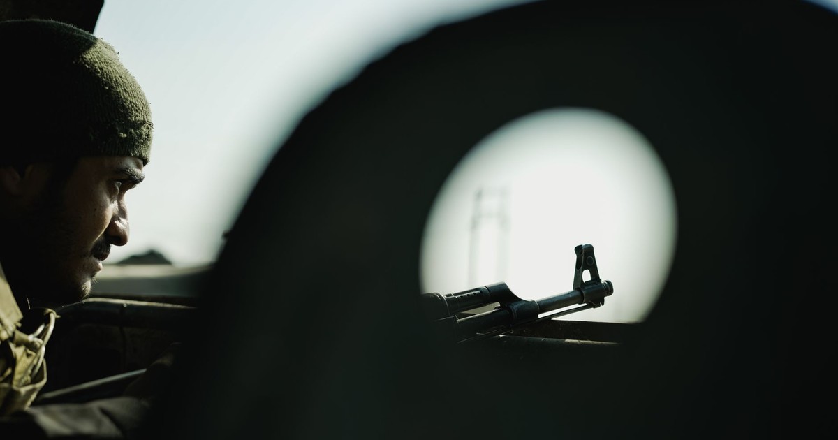 A soldier's profile with a firearm silhouetted against a blurred background, creating a tense atmosphere.