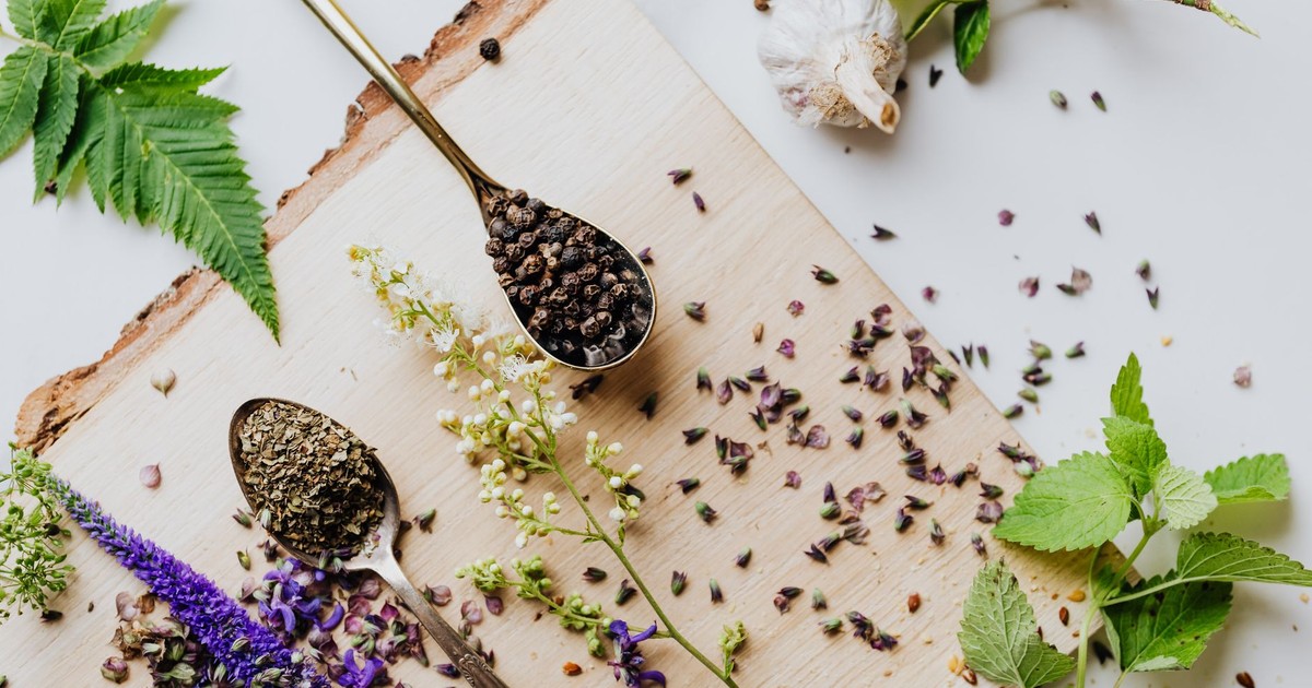 A top view of dried and fresh herbs on a wooden board, perfect for culinary and medicinal uses.