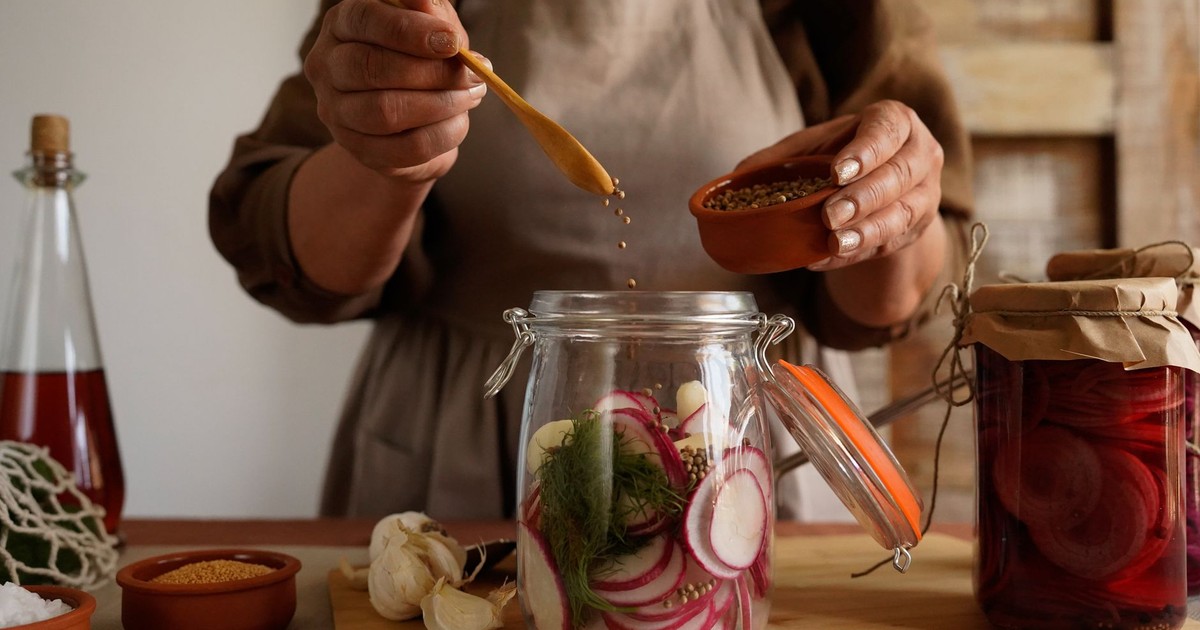 Hands preparing pickled vegetables in a jar, capturing a rustic and organic lifestyle.