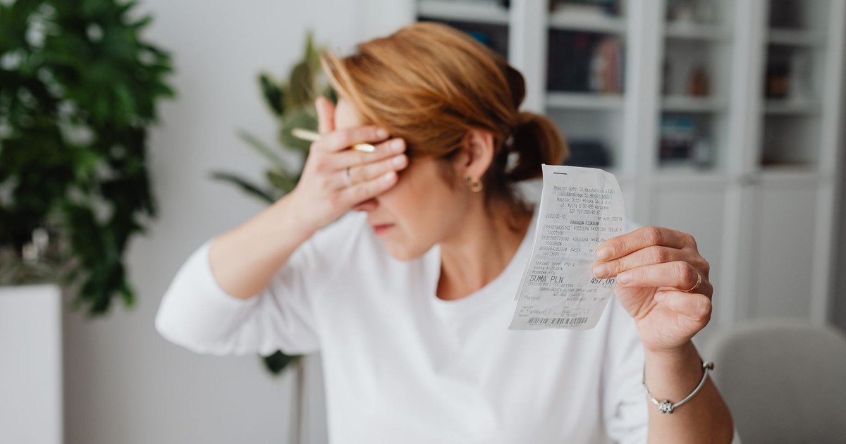 Woman experiencing stress while reviewing household expenses at home.