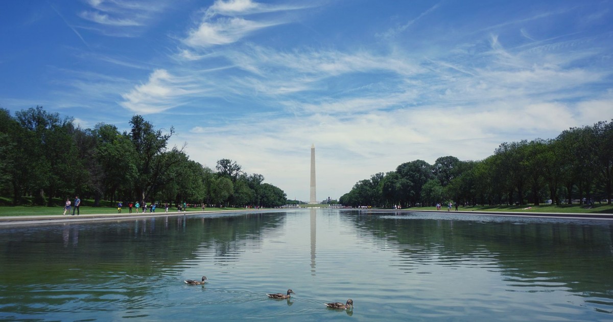 A serene view of the Washington Monument reflecting in a pool with a vibrant sky above.