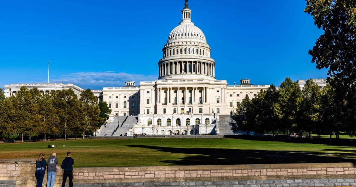 A vibrant daytime photograph of the iconic US Capitol with a clear blue sky backdrop.