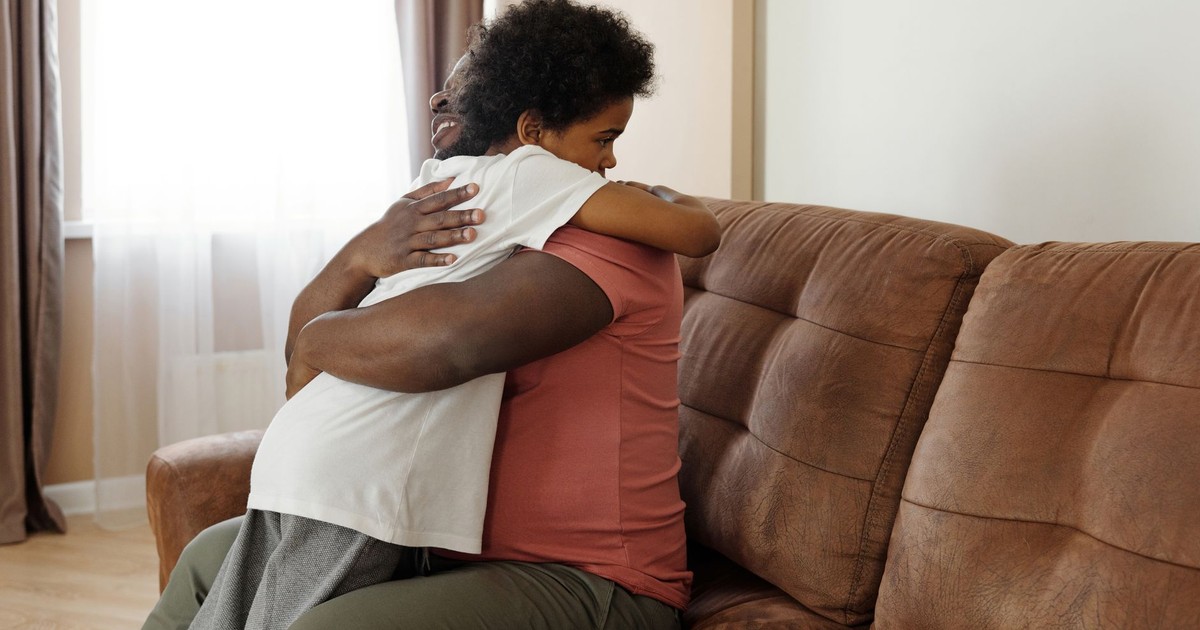 Father and son sharing a warm embrace on the sofa, expressing love and family togetherness.