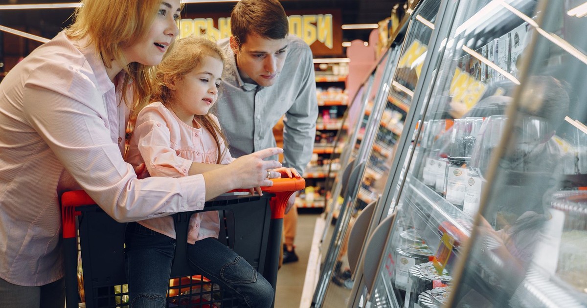 A happy family shopping together in a supermarket, exploring a refrigeration aisle.