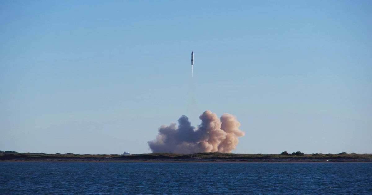 A rocket launch with smoke trails over South Padre Island, viewed across the ocean.