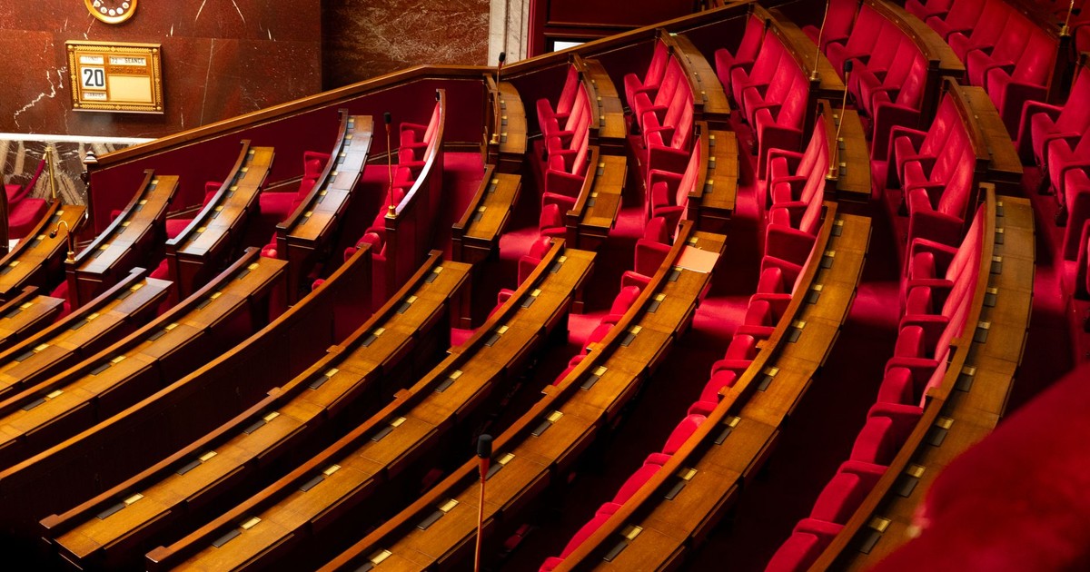 A luxurious interior view of a legislative chamber with curved red seating and wooden desks.