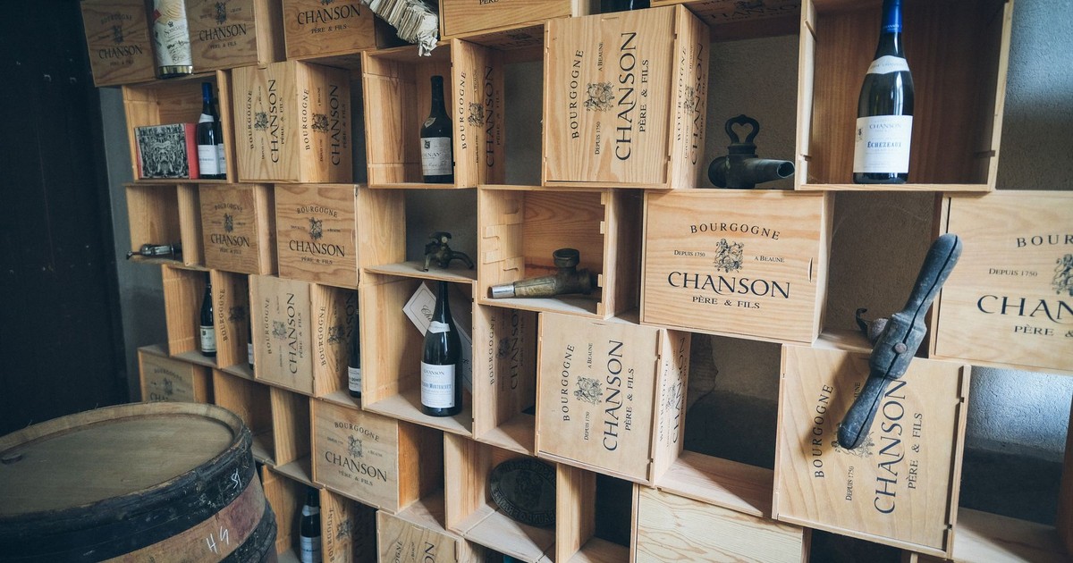 Rustic wine cellar featuring wooden shelves filled with Chanson wine crates and vintage bottles.