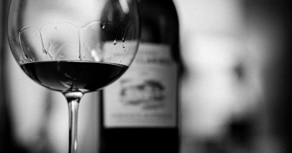 Stylish black and white photo of a wine glass and bottle in focus. Perfect for elegant settings.