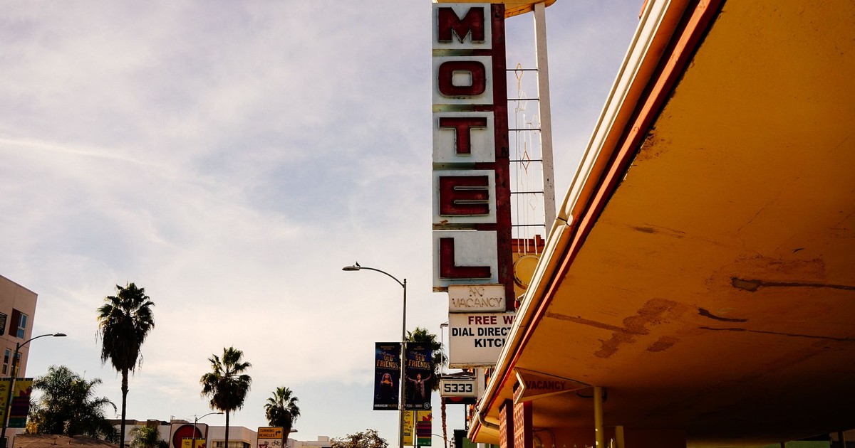 Iconic Hollywood Premiere motel sign against a California sky, framed by palm trees.