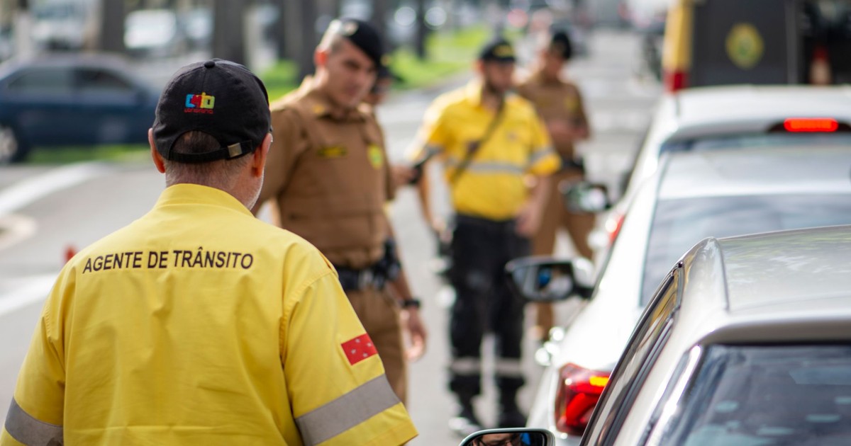 Traffic agent in bright uniform managing vehicles on a busy Londrina street.