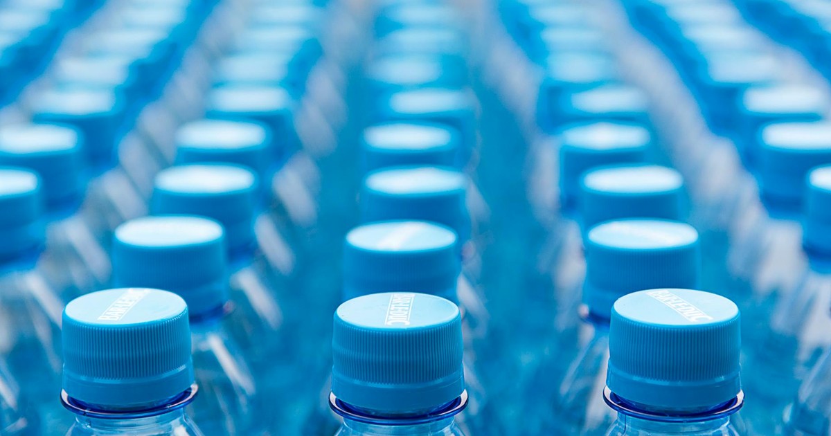 Array of blue plastic water bottles with caps arranged in a pattern. Ideal for recycling and packaging themes.