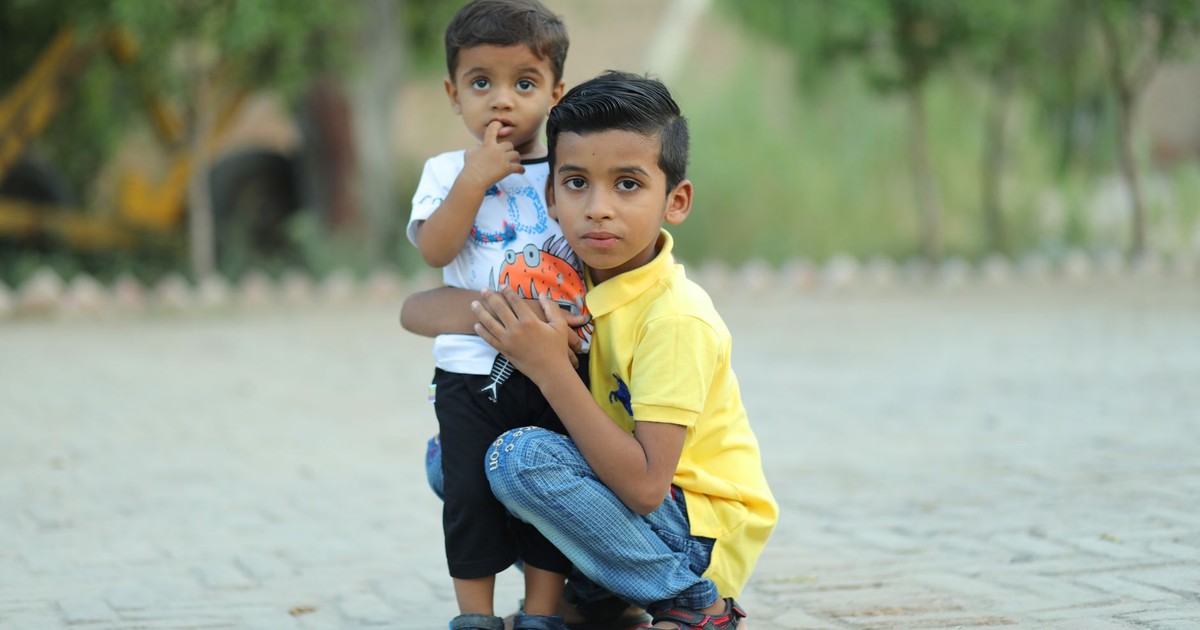 Two young boys embracing outdoors on a sunny day. Captures childhood bond and innocence.