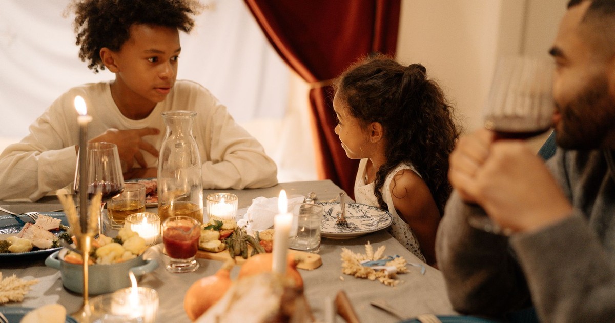 Warm family gathering around a candlelit dinner table, sharing a festive meal indoors.