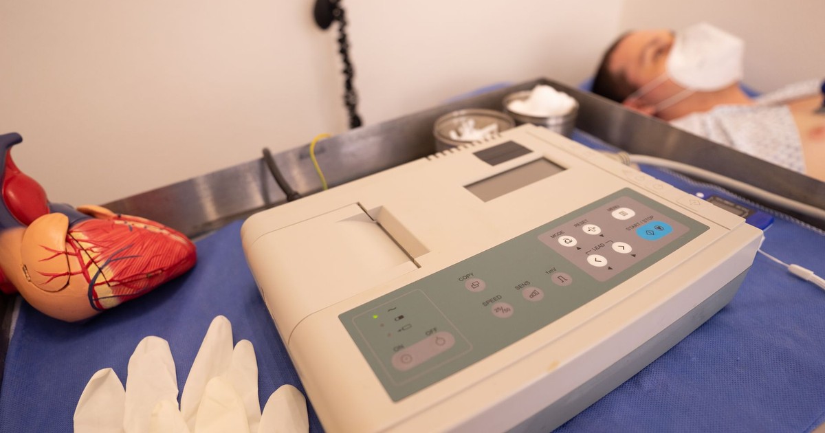 Close-up of ECG machine and model heart in a hospital setting.